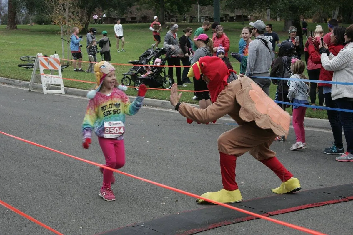 A kid high-fives a runner in a turkey costume at the finish line